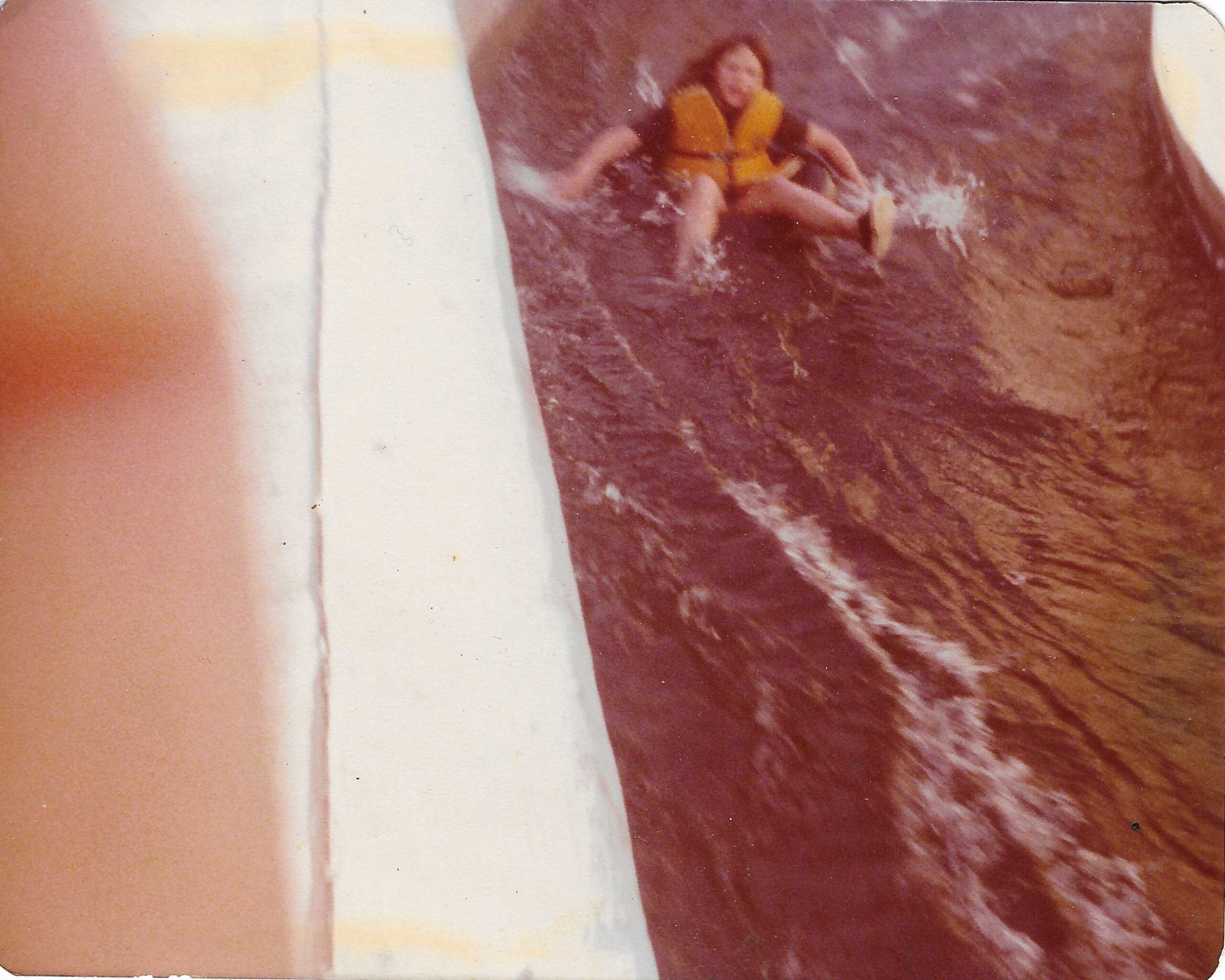 Historical 1977 photograph of a person floating through the center of the Comal River Tube Chute in New Braunfels Texas