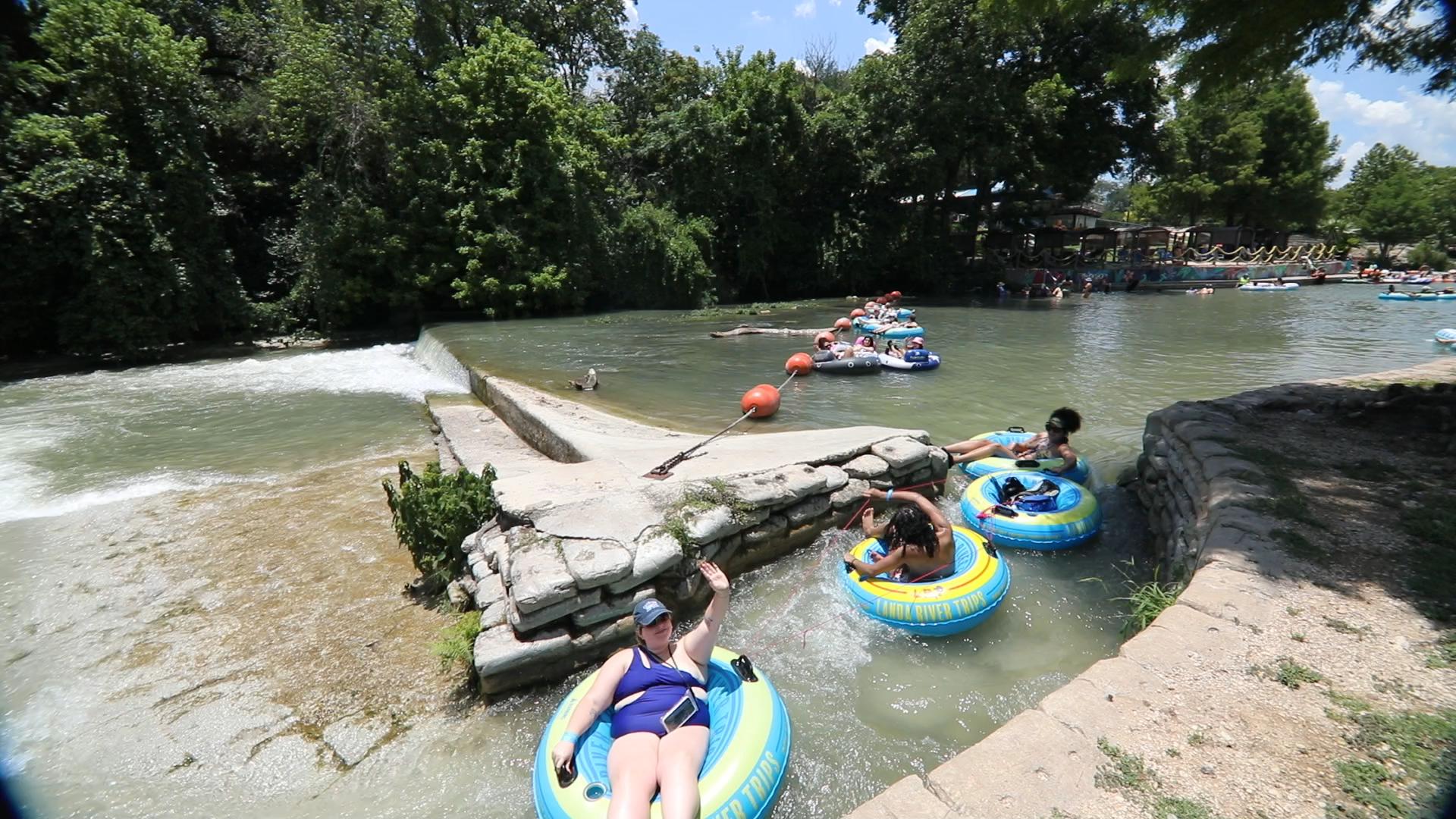 Guests floating the Comal River on Landa River Trips tubes past the dam in New Braunfels Texas
