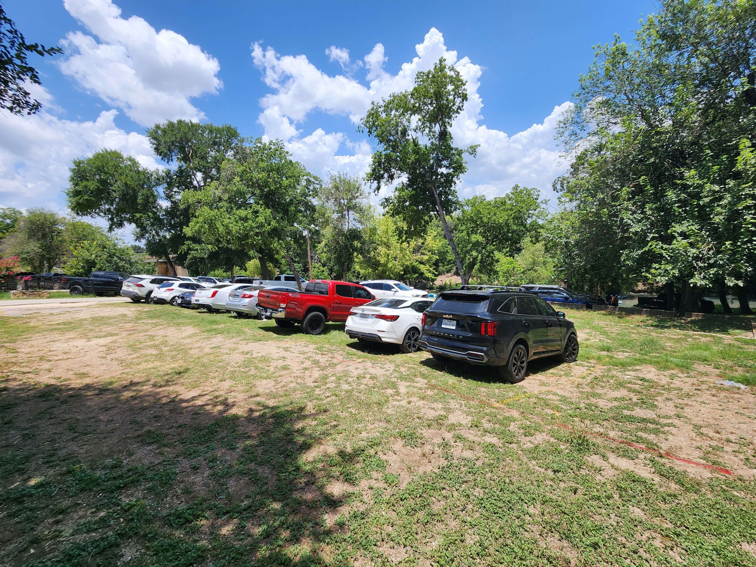 Landa River Trips grass parking lot full of cars for Comal River tubing in New Braunfels Texas