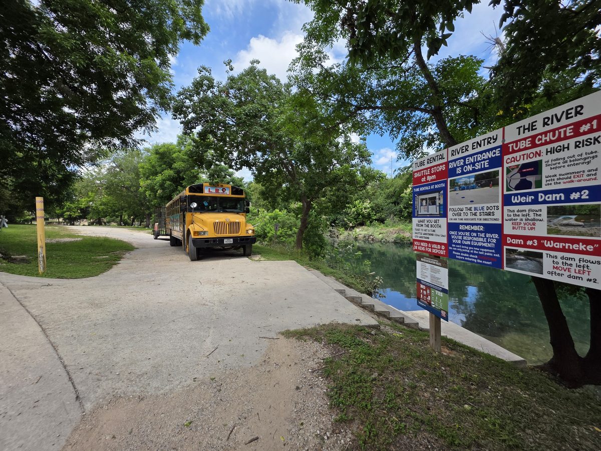 Landa River Trips shuttle bus and river information sign at the Comal River entry point in New Braunfels Texas