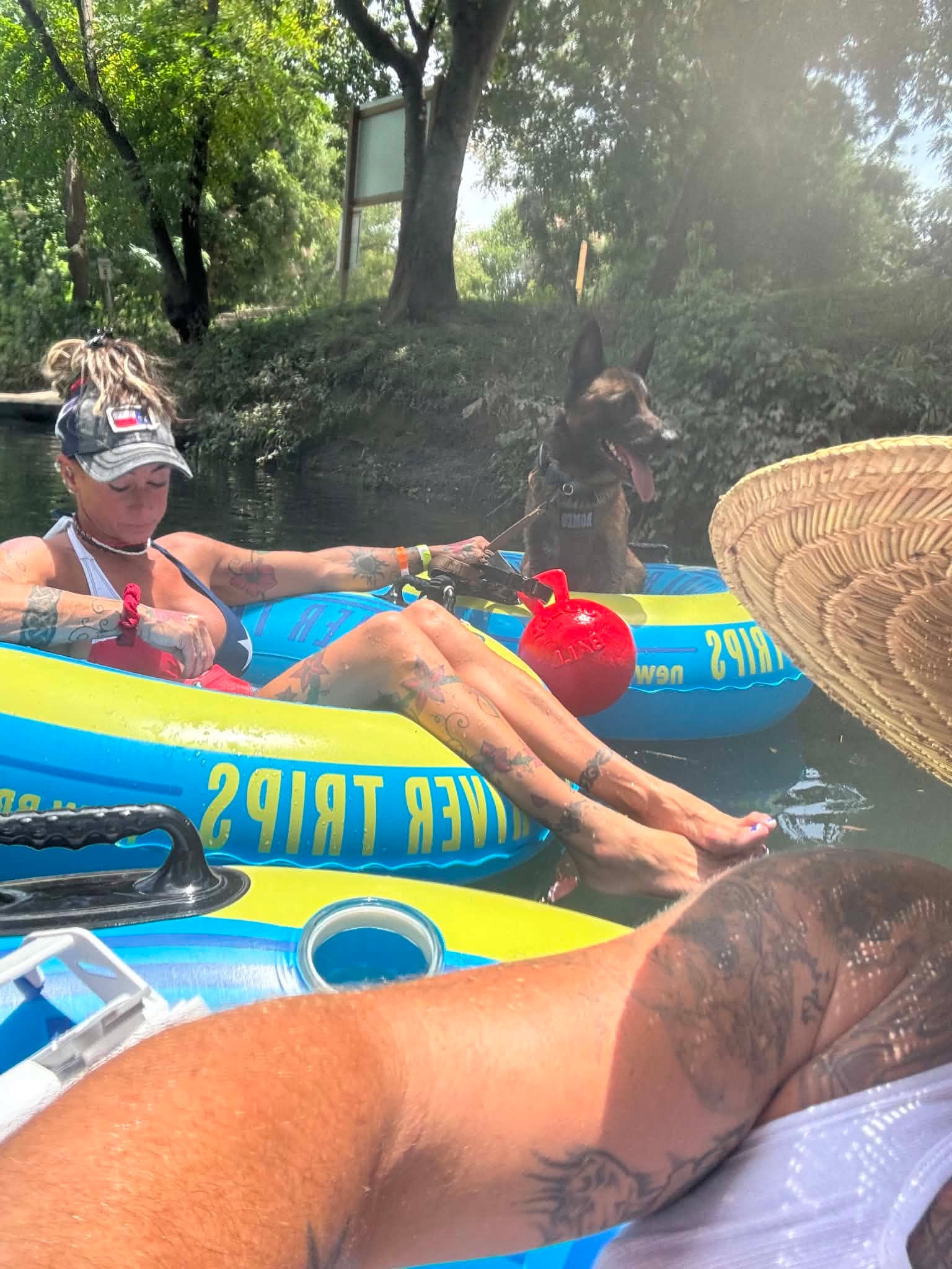 Family floating the Comal River with their dog along the bank at Landa River Trips